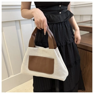 Detail of minimalist cream canvas tote bag featuring brown leather trim and sturdy stitching