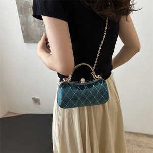 Detail of dark green velvet handbag with diamond lattice and golden metal handle