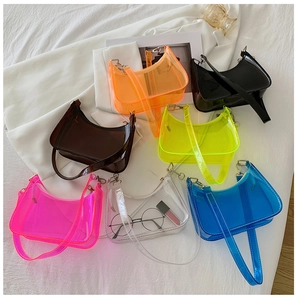 Flat lay of colorful PVC half-moon shoulder bags with silver hardware on white fabric