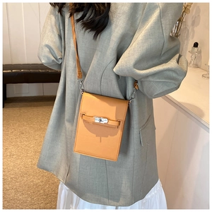 Detail of an orange textured leather crossbody bag with a classic metal twist lock buckle