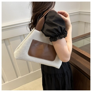 Detail of minimalist beige canvas tote bag with brown leather handles worn on shoulder