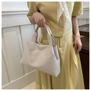 Primer plano del bolso tote de cuero trenzado crema mostrando el patrón de tejido