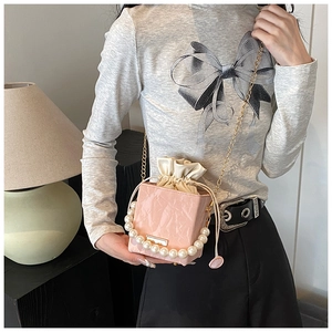 Détail d'un sac seau plissé rose avec poignée en perles et bandoulière chaîne dorée