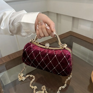 Detail of burgundy velvet clutch with quilted pattern and rhinestone ball clasp on gold frame