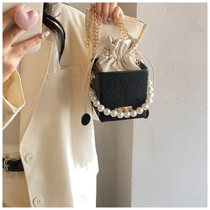 Detail of a black square mini bag with pearl handle and drawstring inner pouch