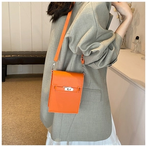 Détail d'un mini sac bandoulière en cuir orange avec un fermoir en métal argenté