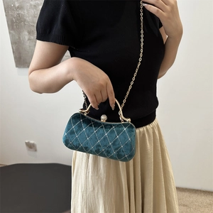 Close-up of dark green velvet evening bag with diamond lattice pattern and chain strap