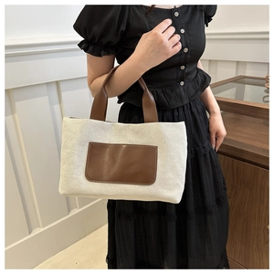 Detailed view of canvas tote bag with brown leather accents on a female model