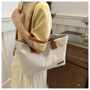 Detailed view of the retro canvas tote bag showing cream fabric and brown leather straps