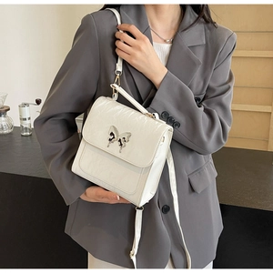 Detail of white square crossbody bag featuring wrinkled patent leather and butterfly buckle