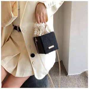 Détail du sac seau bicolore chic avec poignée en perles et bandoulière dorée