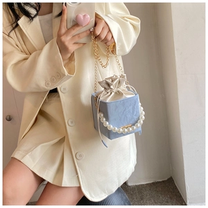 Detail of light blue PU cube bag with elegant pearl handle and gold metal chain strap