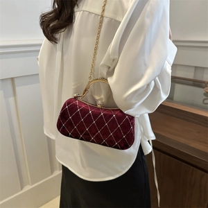 Close-up of burgundy velvet evening bag with diamond lattice pattern and gold chain