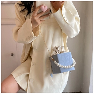 Detail of light blue cube crossbody bag with pearl handle and golden chain strap