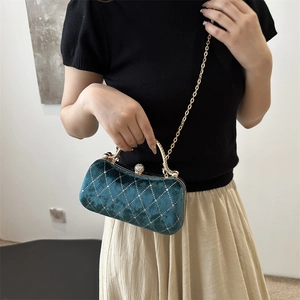 Close-up of velvet handbag featuring rhinestone lattice pattern and gold metal handle