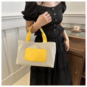Detail of canvas tote bag showing cream fabric texture and yellow PU leather handle
