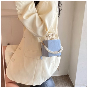 Détail du sac seau bleu clair avec poignée en perles élégante et fermeture en soie