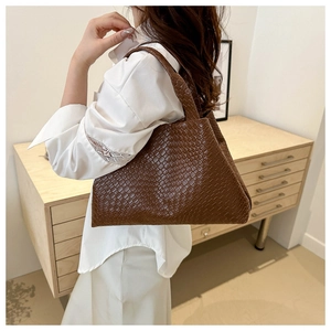 Primer plano de un bolso tote de cuero trenzado marrón vintage con textura tejida