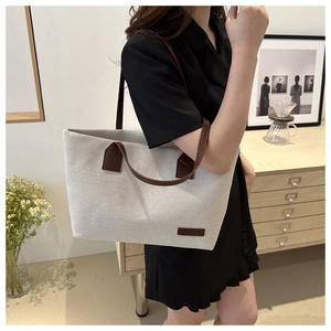 Lifestyle shot of large canvas tote bag with brown straps in a cozy room setting