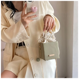 Detail of green bucket bag with pearl handle, chain strap, and drawstring closure