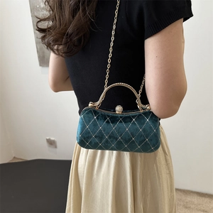 Detail of green velvet evening bag with diamond lattice pattern and gold handle on model
