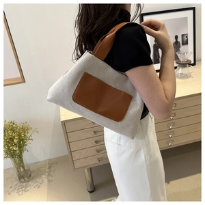 Detail of canvas tote bag with brown leather handles worn by a model in a home setting