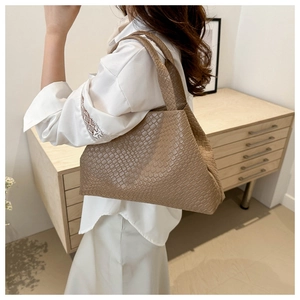 Detail shot of a brown woven bucket bag with leather texture on a female model