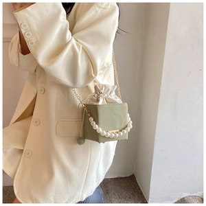 Détail du sac boîte vert avocat avec poignée en perles, cordon de serrage et chaîne dorée