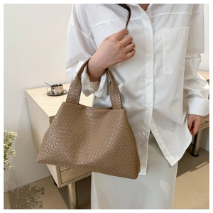 Detail of a brown quilted woven tote bag with a vintage crocodile texture and soft handle