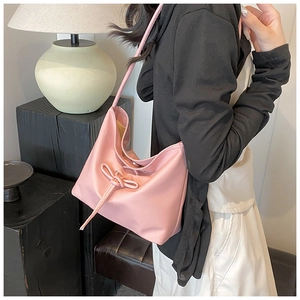 Pink PU leather shoulder bag featuring drawstring bow detail and minimalist soft bucket design