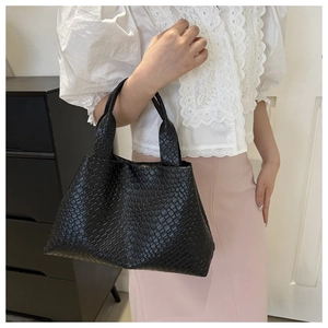 Close-up of black woven leather tote bag with glossy diamond pattern and sturdy handles