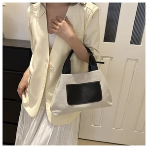 Detail of canvas tote bag with contrast black leather handles and fine stitching accents