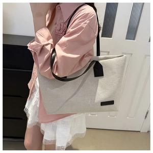 Detail of canvas tote bag with black leather label and long shoulder straps