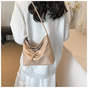 Détail d'un sac à bandoulière beige avec cordon de serrage et nœud en cuir synthétique