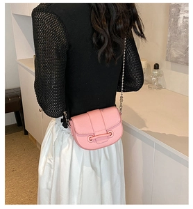 Vue détaillée du sac besace rose avec chaîne en argent porté par un mannequin