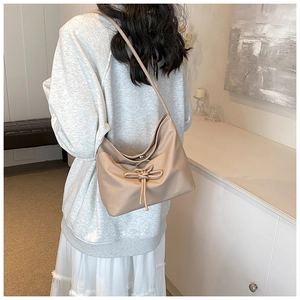 Détail d'un sac cabas kaki souple avec décoration de nœud papillon sur un mannequin