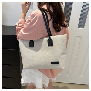 Oatmeal canvas tote bag with black leather handles and fashion patch for daily commute