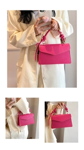 Detail of a rose pink textured leather bag with twisted rope handle and gold hardware