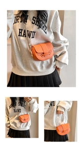Détail d'un sac besace orange avec texture cuir grainé et fine bandoulière chaîne