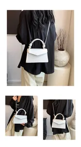 White leather crossbody bag with knot handle and lychee texture shown on a model