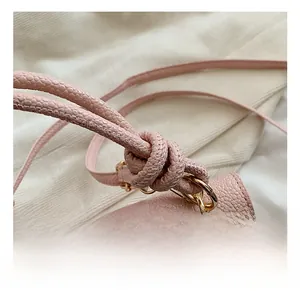 Close-up of pink lychee grain leather bag with round gold hardware and knotted strap