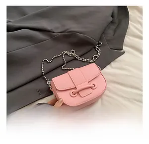 Détail du sac selle rose avec texture litchi et chaîne à perles sur tissu de costume