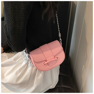 Gros plan sur un sac selle en cuir grainé rose avec chaîne à perles argentées sur modèle