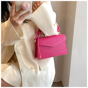 Detail of bright pink litchi grain leather bag featuring a unique braided rope handle