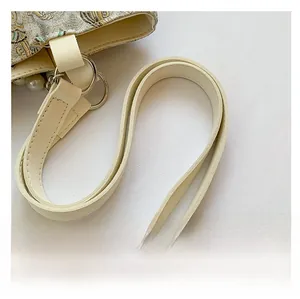 Close-up of stylish PU shoulder strap and vintage jacquard fabric with pearl pendant