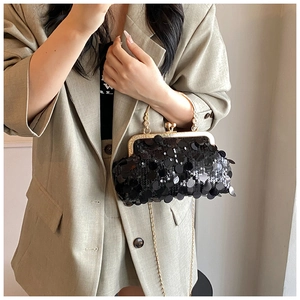 Detail of black sequined evening bag with gold handle and chain strap on a model