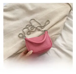 Détail d'un mini sac selle en cuir grainé rose avec breloque étoile et chaîne argentée