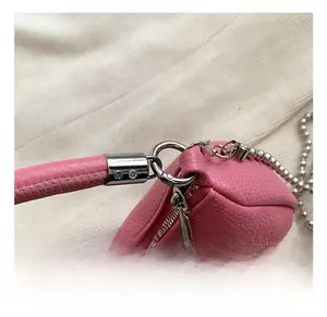 Détail du sac en cuir rose grainé avec crochet en métal argenté et bandoulière perle