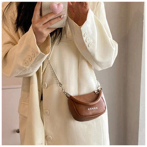 Close-up of brown textured leather saddle bag with silver star studs and bead chain strap