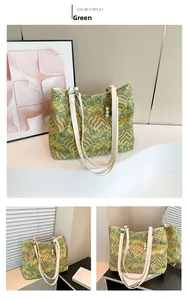 Detail of green silk tote bag featuring wave patterns and pearl clover charm